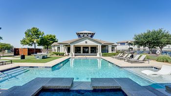 A large swimming pool in front of a house with a deck and sun loungers.